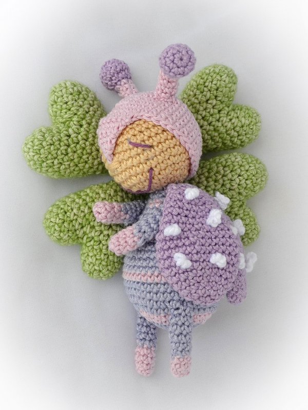 gehäkelte Amigurumi-Käferpuppe in Pastellfarben mit grünen Flügeln