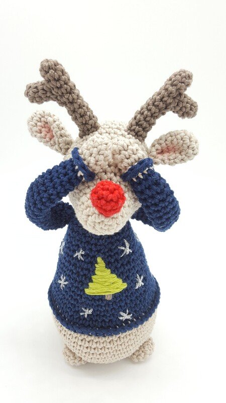 Gehäkeltes Rentier‑Amigurumi mit roter Nase und blauem Weihnachtspullover, Augen mit Ärmeln bedeckt