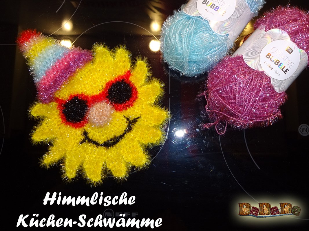 Gehäkelte gelbe Sonne als Küchenschwamm mit Partyhut, Sonnenbrille und Garnknäueln