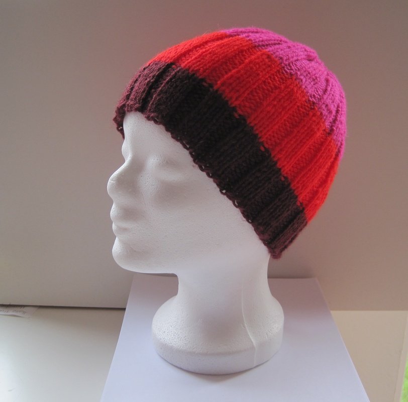 Gestreifte Strickmütze in Dunkelbraun, Rot und Pink auf weißem Mannequinkopf