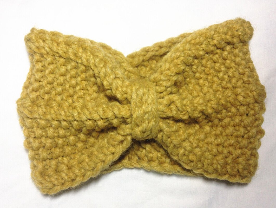 Gestricktes senfgelbes Stirnband mit gedrehtem Knoten in der Mitte