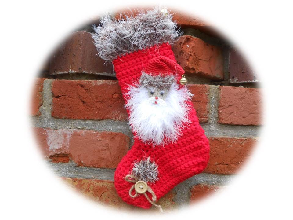 Roter, gehäkelter Weihnachtsstrumpf mit Weihnachtsmann-Applikation an Ziegelwand
