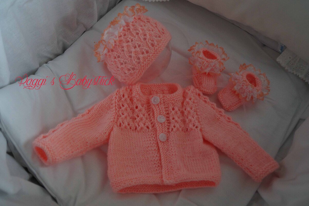 Gestricktes Baby-Set in Lachsrosa: Jäckchen, Mütze und Schühchen auf weißer Unterlage