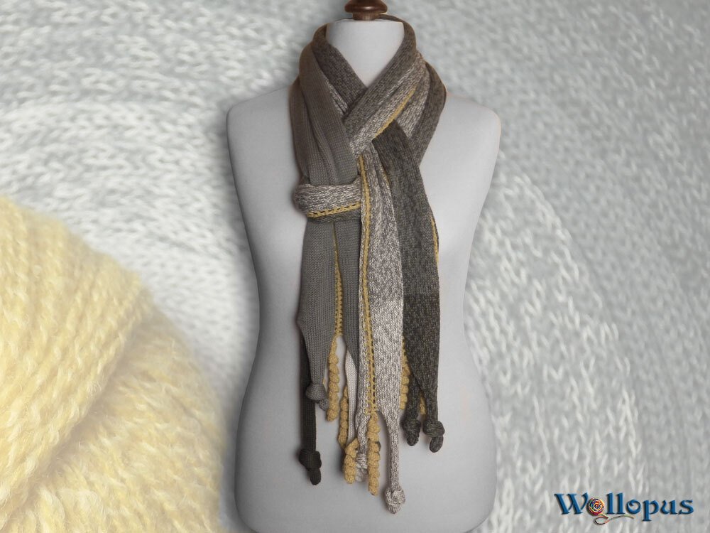 schmaler gestrickter Schal in Grau und Beige mit geknoteten Quasten an einer Schneiderpuppe