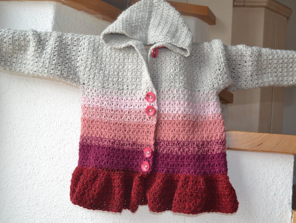 Gehäkelte Kinderjacke in Grau, Rosa und Rot mit Kapuze und fünf rosa Knöpfen