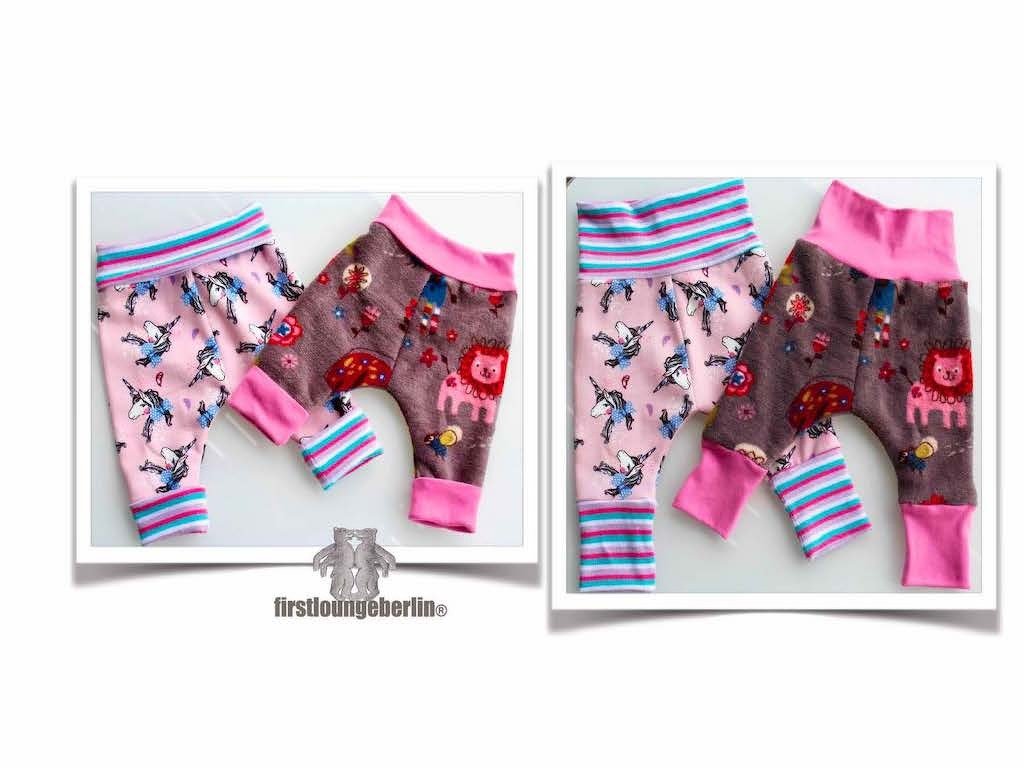 Zwei gemusterte Babyhosen: rosa Einhornhose mit gestreiften Bündchen und braune Hose mit Löwen- und Pilzmotiven