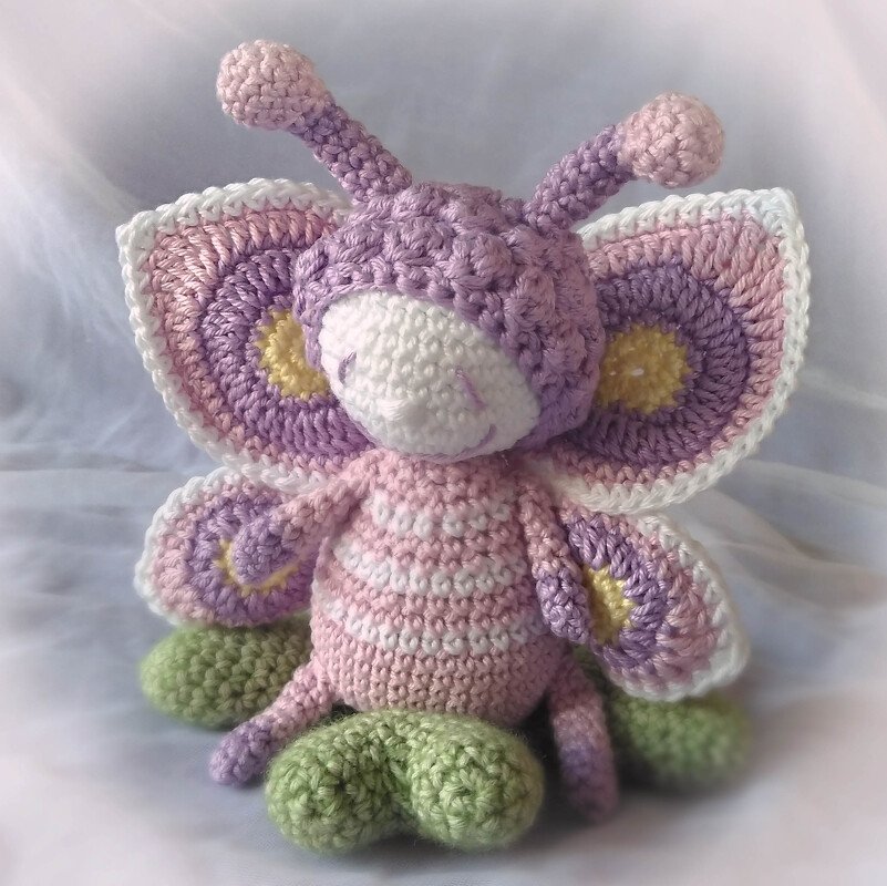 Gehäkelter Schmetterling mit lila-rosa Flügeln und gestreiftem Körper