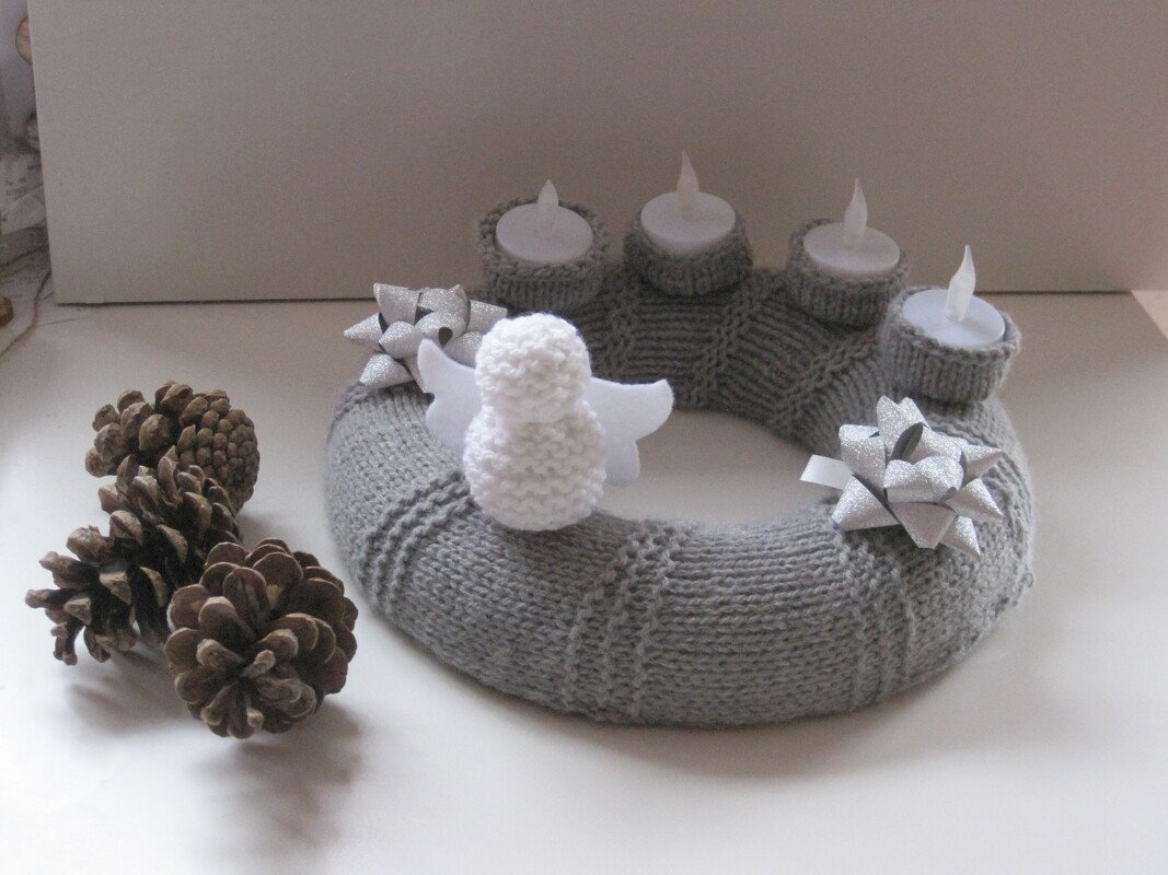 Gestrickter grauer Adventskranz mit vier Teelichtern, weißem Engel, silbernen Schleifen und Tannenzapfen