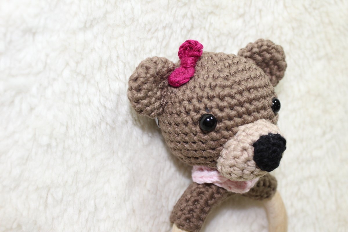 Gehäkelter Bärenkopf an Holz-Greifring, braunes Garn, rosa Schleife
