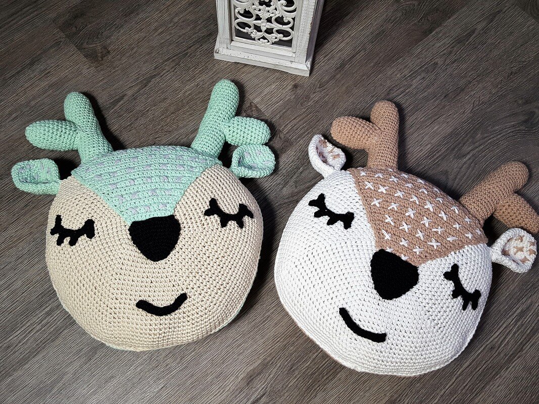 Nahaufnahme zweier gehäkelter Rentier-Kissen mit verschiedenen Stichmustern und Geweihen