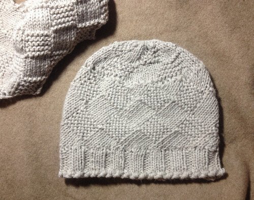 Hellgraue gestrickte Damenmütze mit Rautenstruktur und Rippbündchen auf neutralem Untergrund