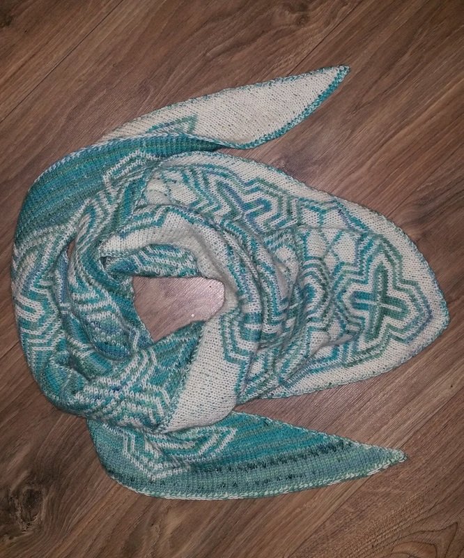 Gestricktes dreieckiges Tuch in creme und türkis mit geometrischem Mosaikmuster, auf Holzboden drapiert