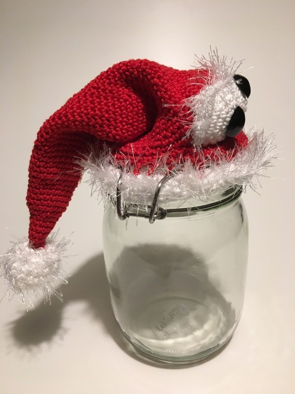 Einmachglas mit roter gehäkelter Weihnachtsmütze mit weißem, flauschigem Rand und Bommel
