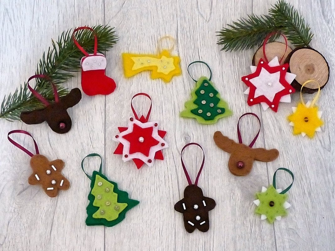 Bunte Filzanhänger in Stern-, Tannen-, Lebkuchen- und Rentierformen auf hellem Holzboden