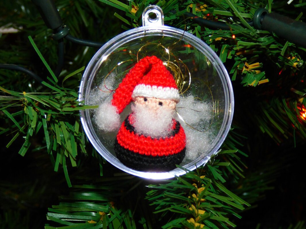 Gehäkelter Mini‑Nikolaus in transparenter Kugel am Tannenzweig