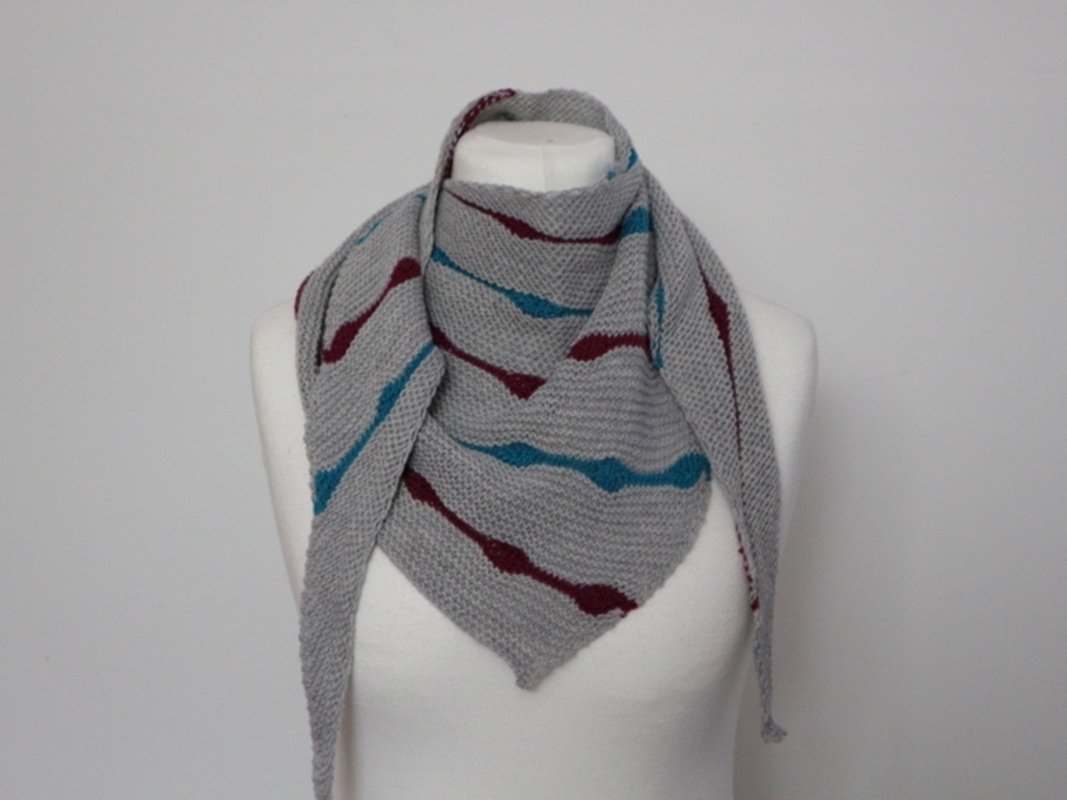Gestricktes graues Dreieckstuch mit türkisen und bordeauxfarbenen Wellenstreifen auf weißer Schaufensterpuppe