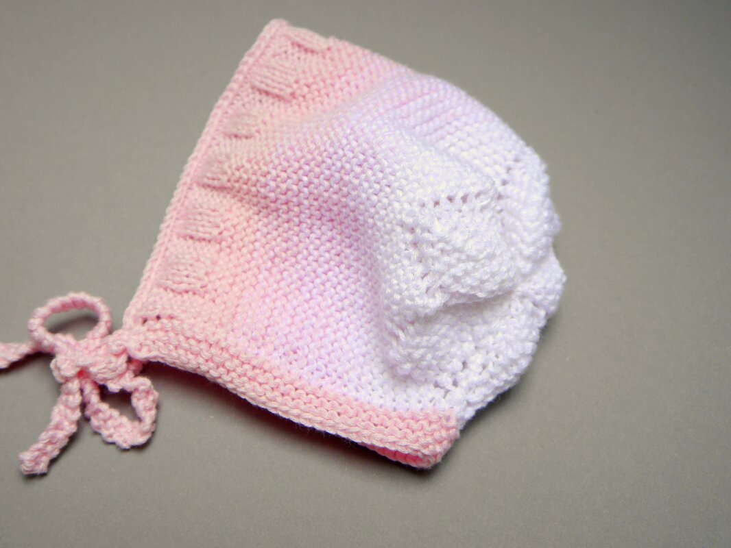 Gestrickte Babyhaube in Rosa und Weiß mit Bindebändern