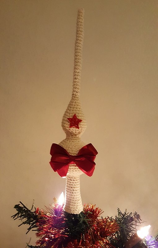 Gehäkelte weiße Christbaumspitze mit rotem Stern und roter Schleife