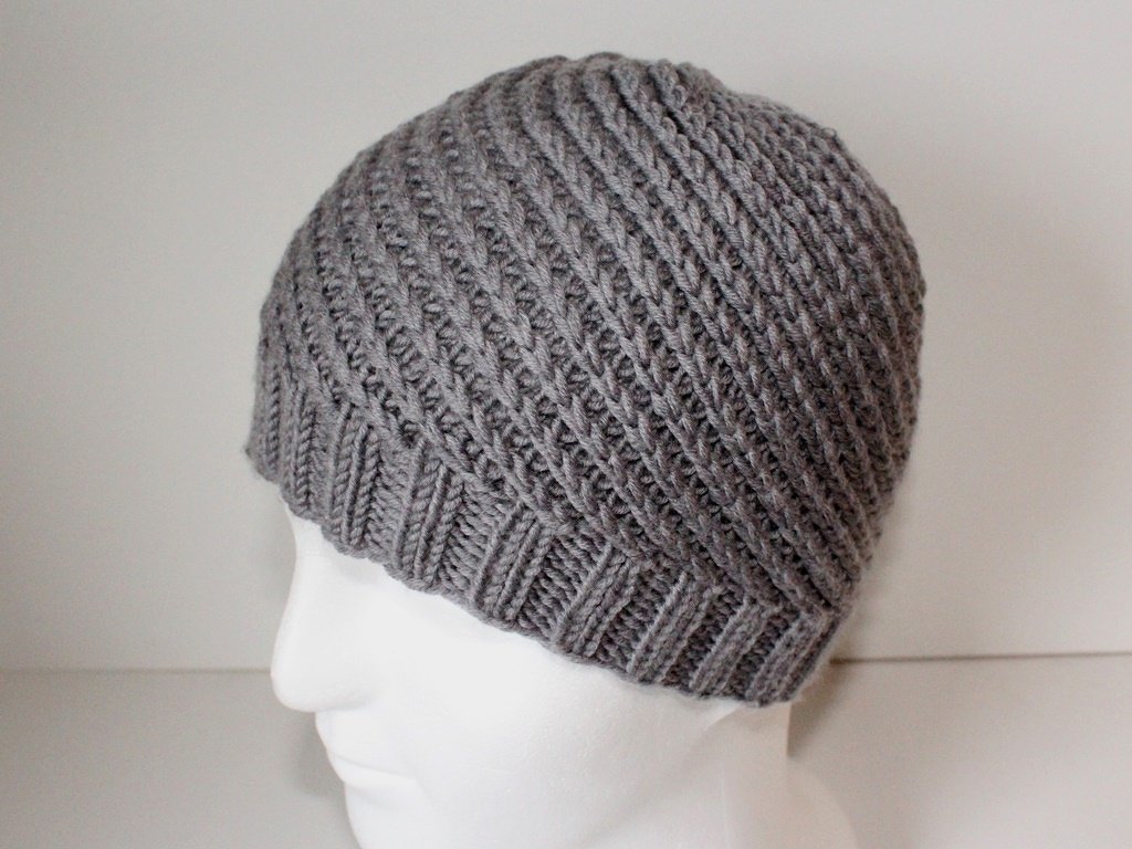 Grau gestrickte Beanie mit diagonaler Rippenstruktur auf weißem Schaufensterkopf