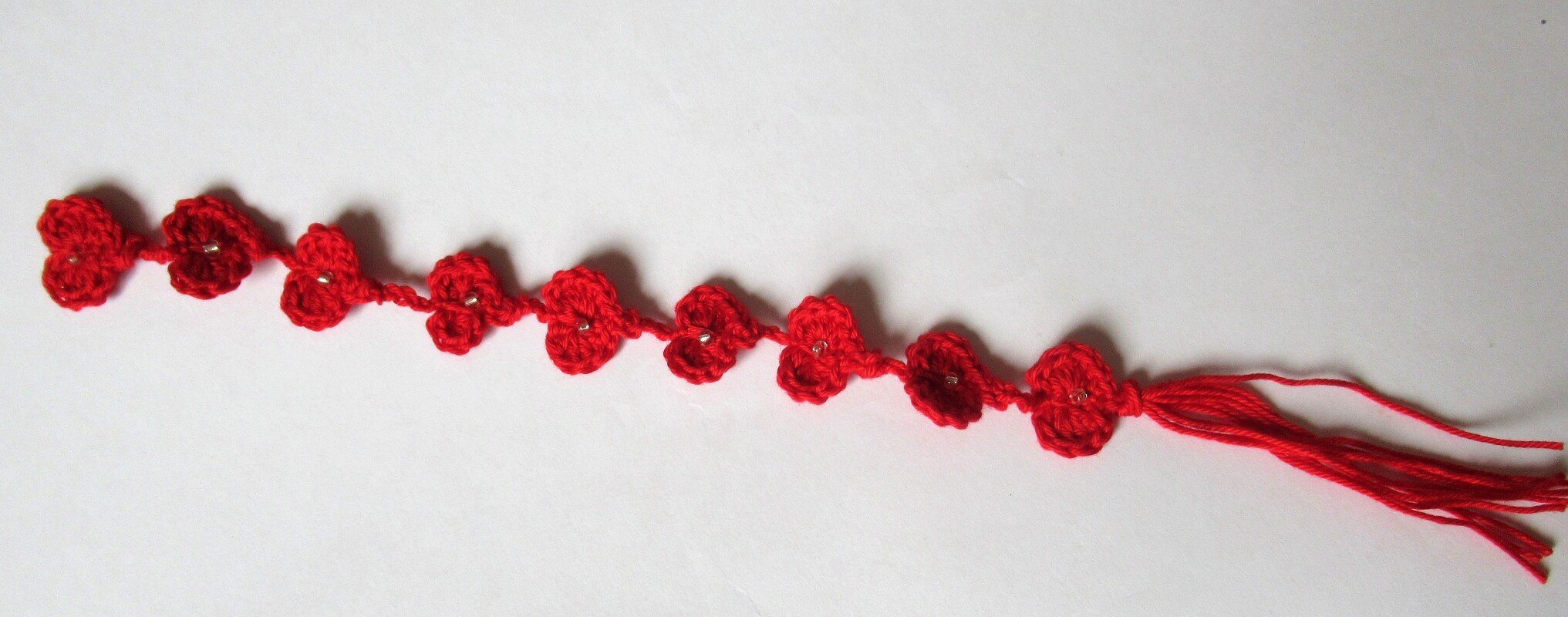 Rotes gehäkeltes Lesezeichen mit Blüten, Perlen und Quaste