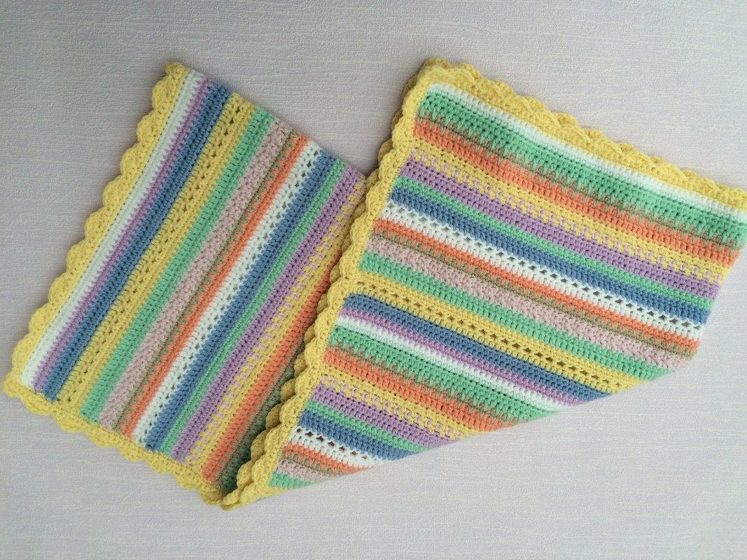 Gehäkelte Babydecke mit pastellfarbenen Streifen und gelbem Muschelrand, gefaltet