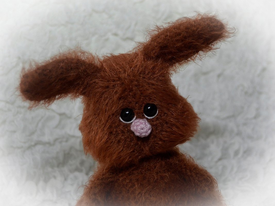 Flauschiger brauner Amigurumi‑Hase mit großen schwarzen Augen und einer rosa gehäkelten Nase