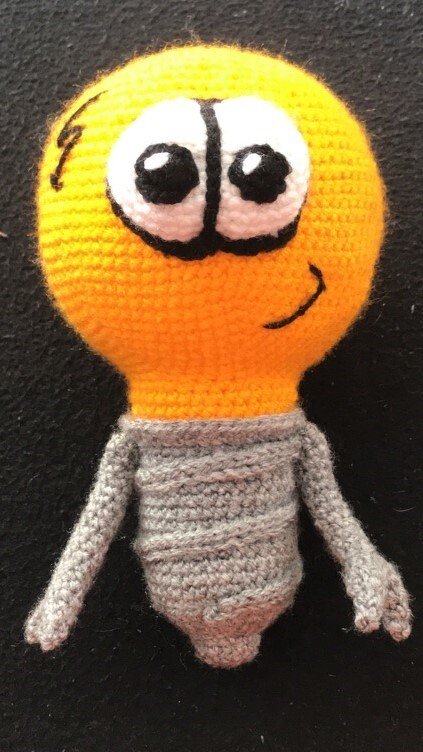Gehäkelte Amigurumi-Glühbirne gelb-grau mit lächelndem Gesicht