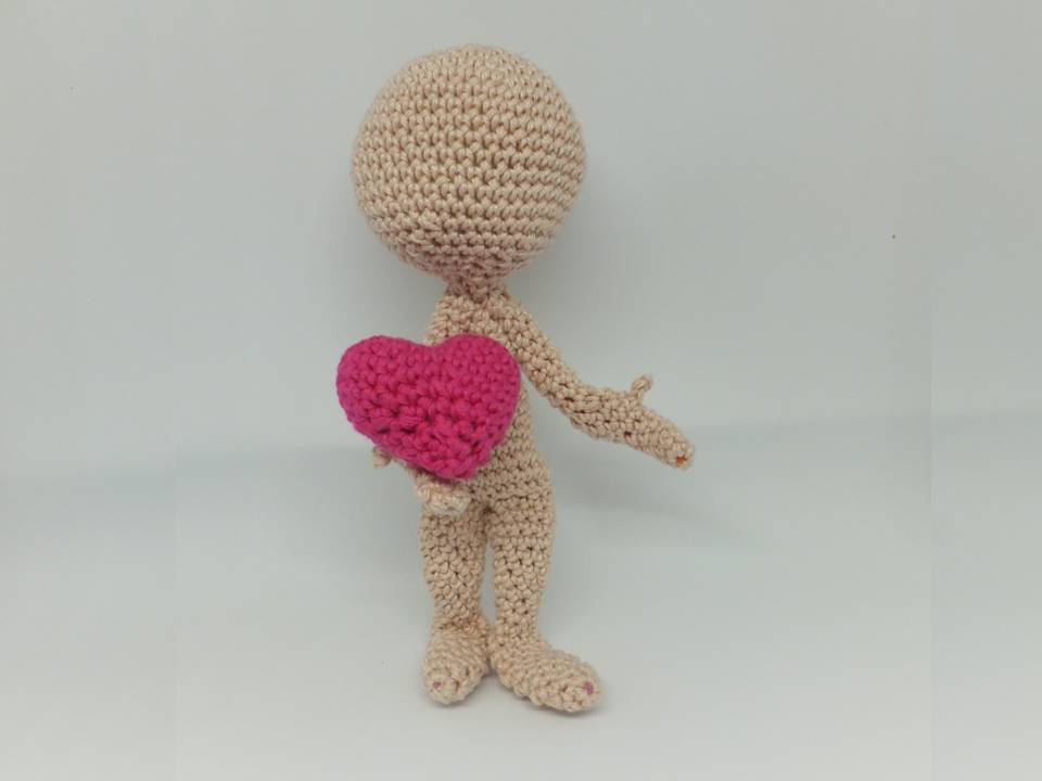 Beige gehäkelte Amigurumi-Puppe hält rosa Herz
