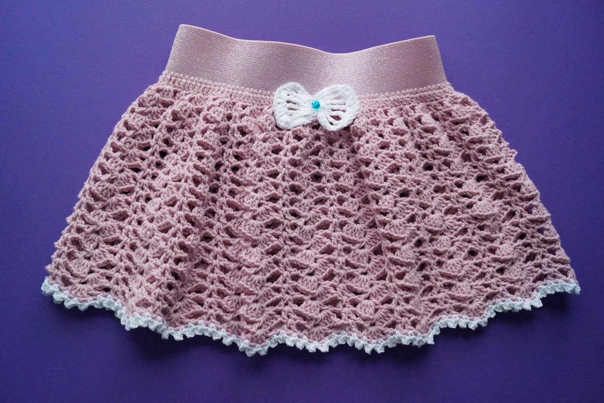 Rosa gehäkelter Kinderrock mit Lochmuster, weißer Picot-Kante und Schleife