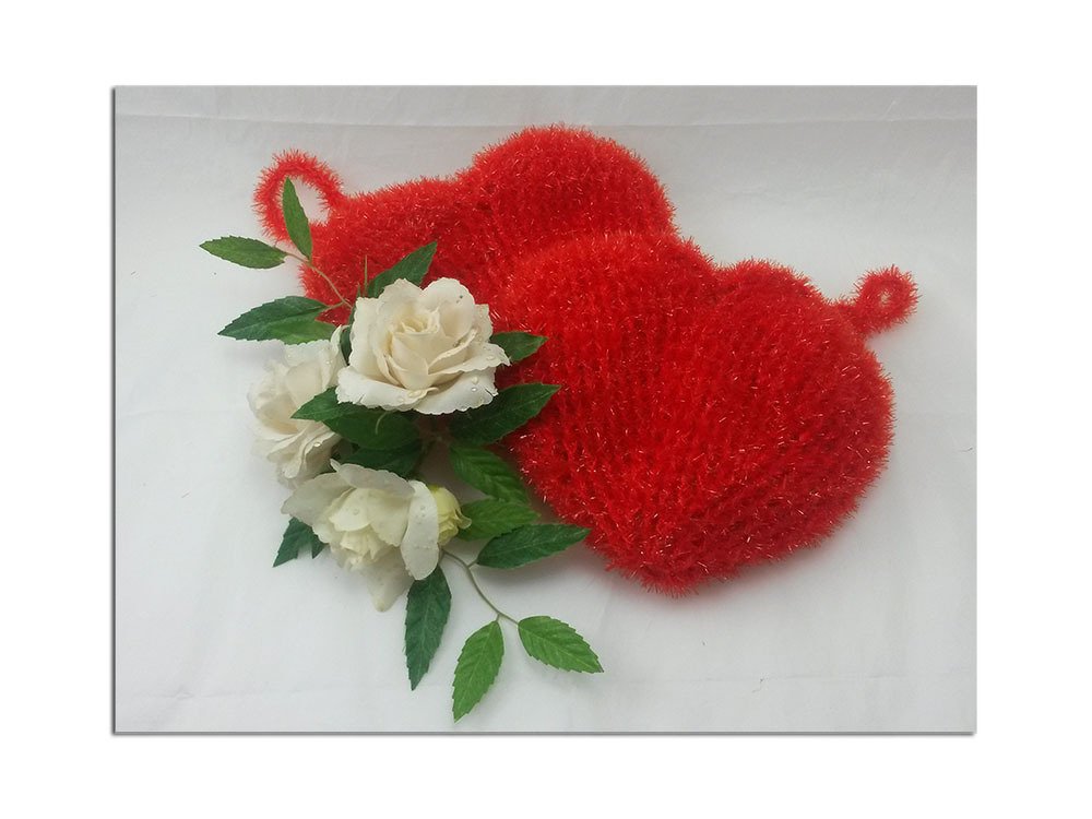 Flauschige gehäkelte Herzanhänger mit Schlaufen neben weißen Rosen