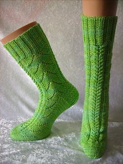 Zwei hohe, grüne handgestrickte Damensocken mit Zopfmuster auf Schaufensterpuppenbeinen