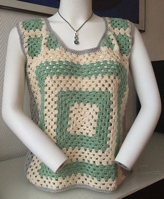 Schaufensterpuppe trägt gehäkeltes Damen-Top aus großen Granny-Squares in Creme, Pastellgrün und grauem Rand