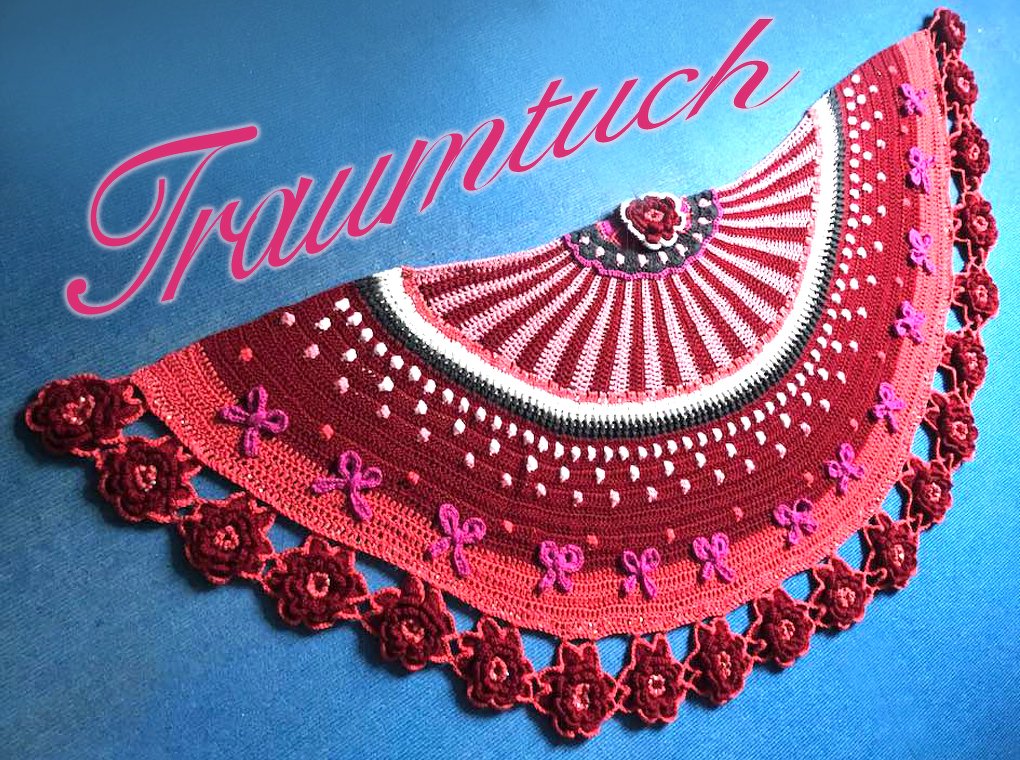 Halbrundes rot-rosa gehäkeltes Tuch mit Rosenkante und Schleifenapplikationen auf blauem Stoff