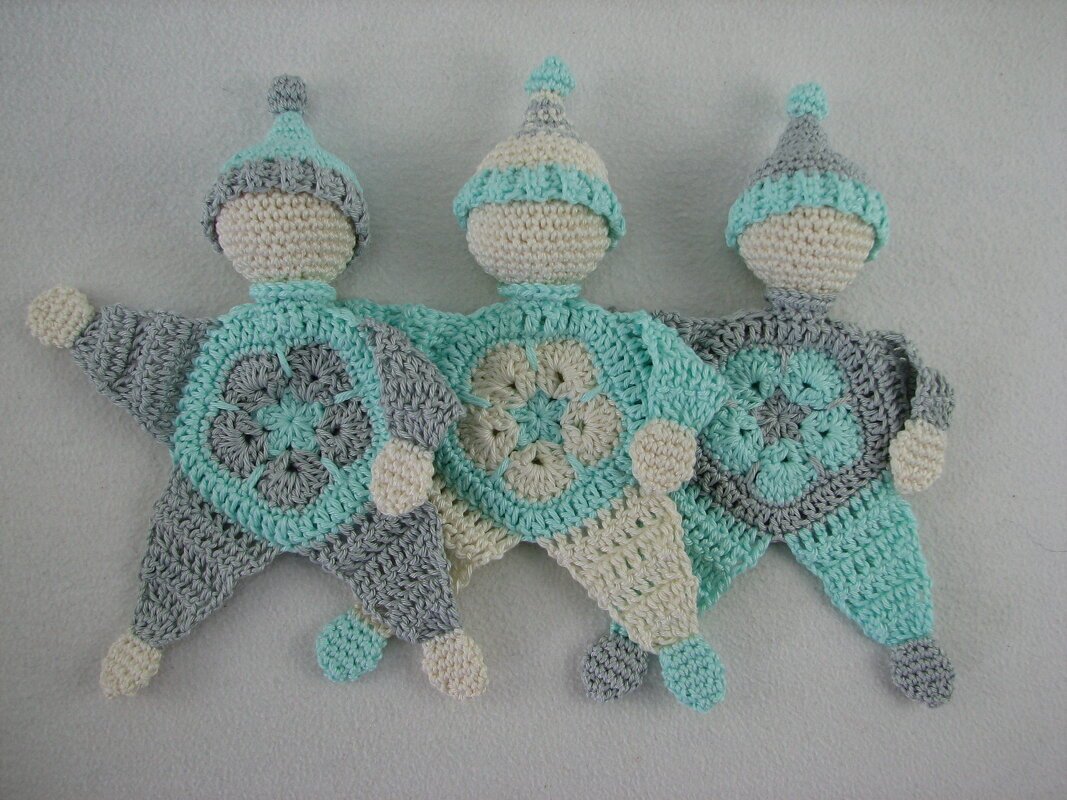 Drei gehäkelte Babyschmusetücher mit sternförmigem Körper und Mütze in Mint, Grau und Creme.