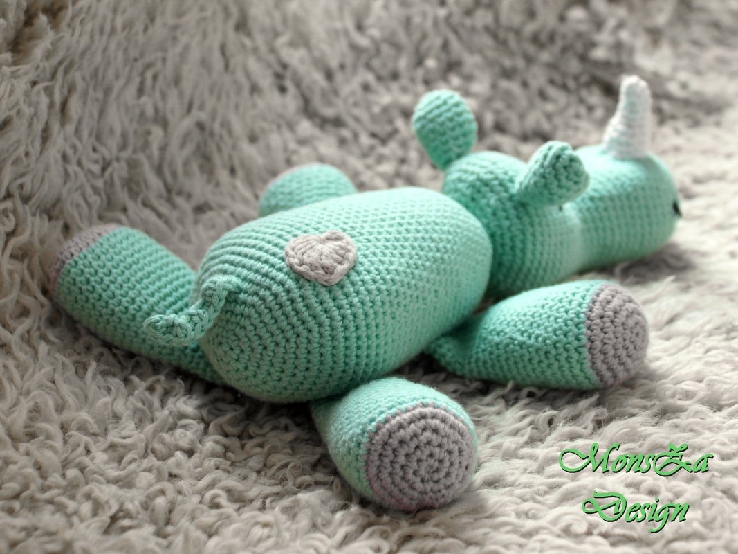 Mintgrünes gehäkeltes Einhorn-Amigurumi mit grauen Hufen und kleinem Herz auf flauschigem Untergrund
