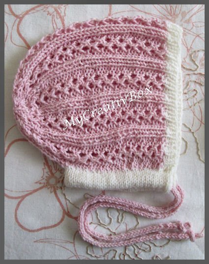 Handgestrickte Babyhaube in Rosa mit weißem Rand und Lochmuster