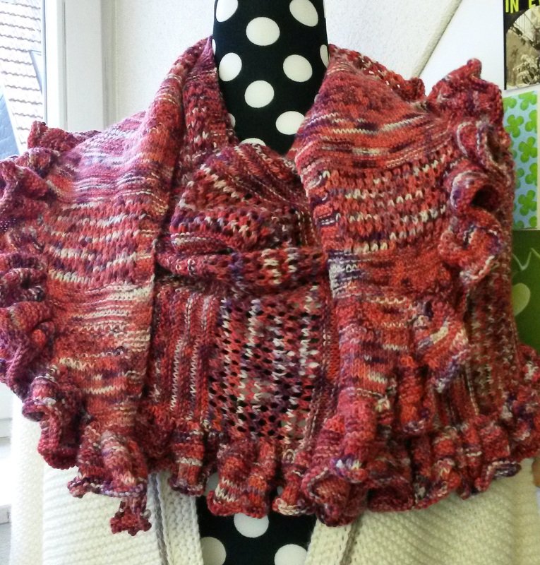 Halbrundes Stricktuch in Rot- und Rosatönen mit Lochmuster und Rüschen auf gepunkteter Schneiderpuppe