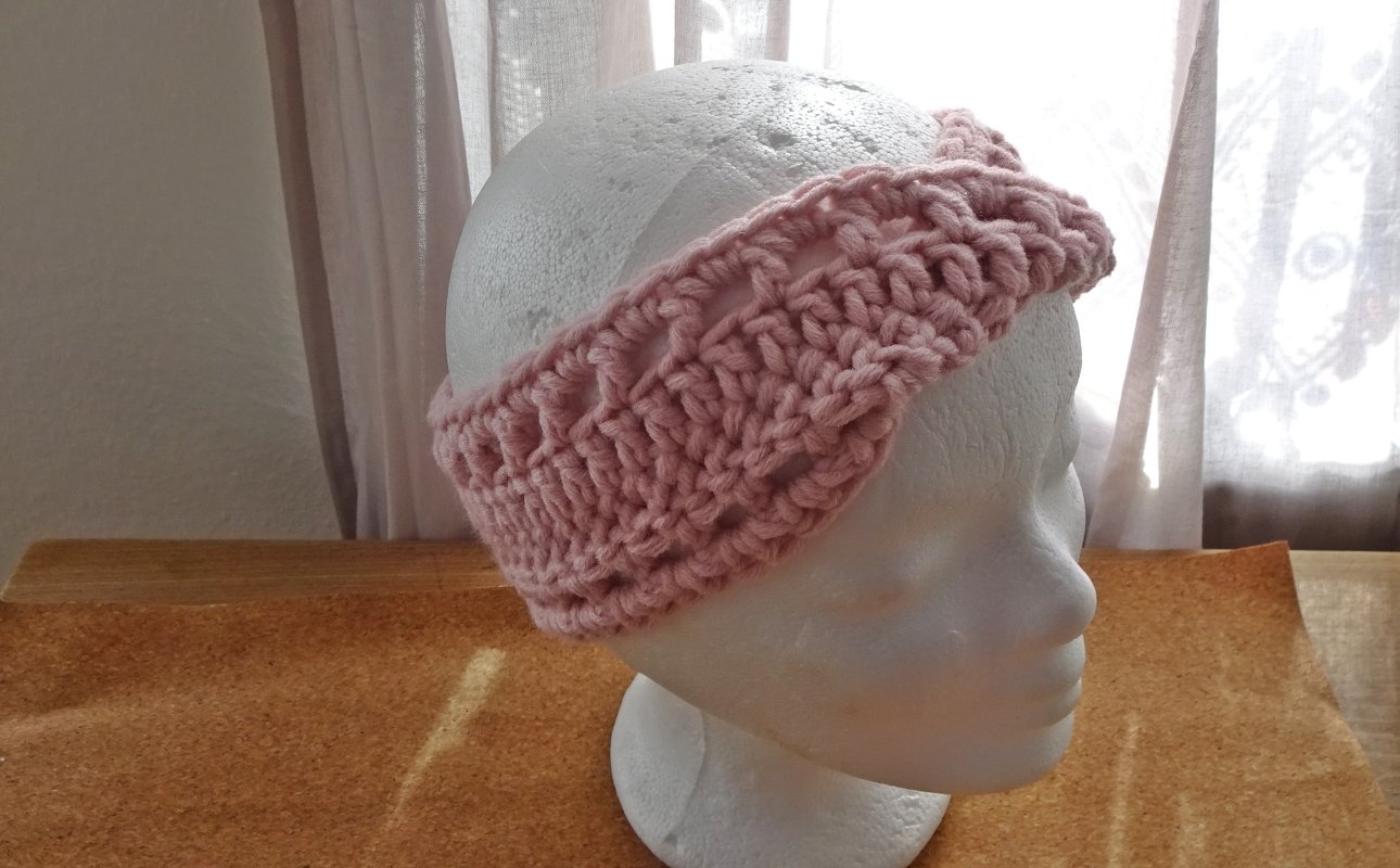Nahaufnahme rosa Stirnband mit dickem Maschenmuster auf Kopfattrappe