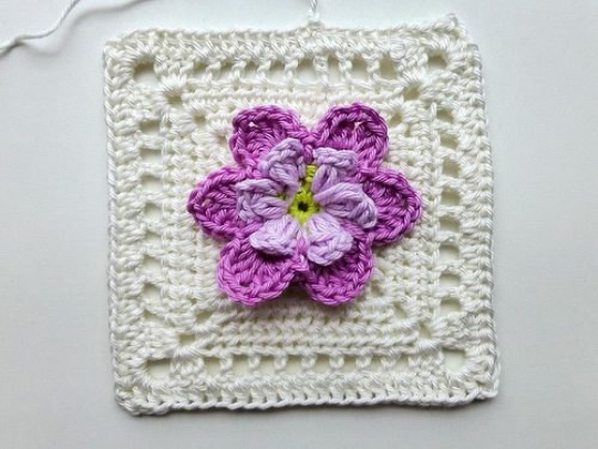 Weiße Granny-Umrandung mit zweilagiger lila Blüte und grünem Mittelpunkt