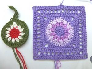 Ansicht einer runden, gehäkelten Blumenapplikation und eines quadratischen lila Granny Squares mit Blumenmittel