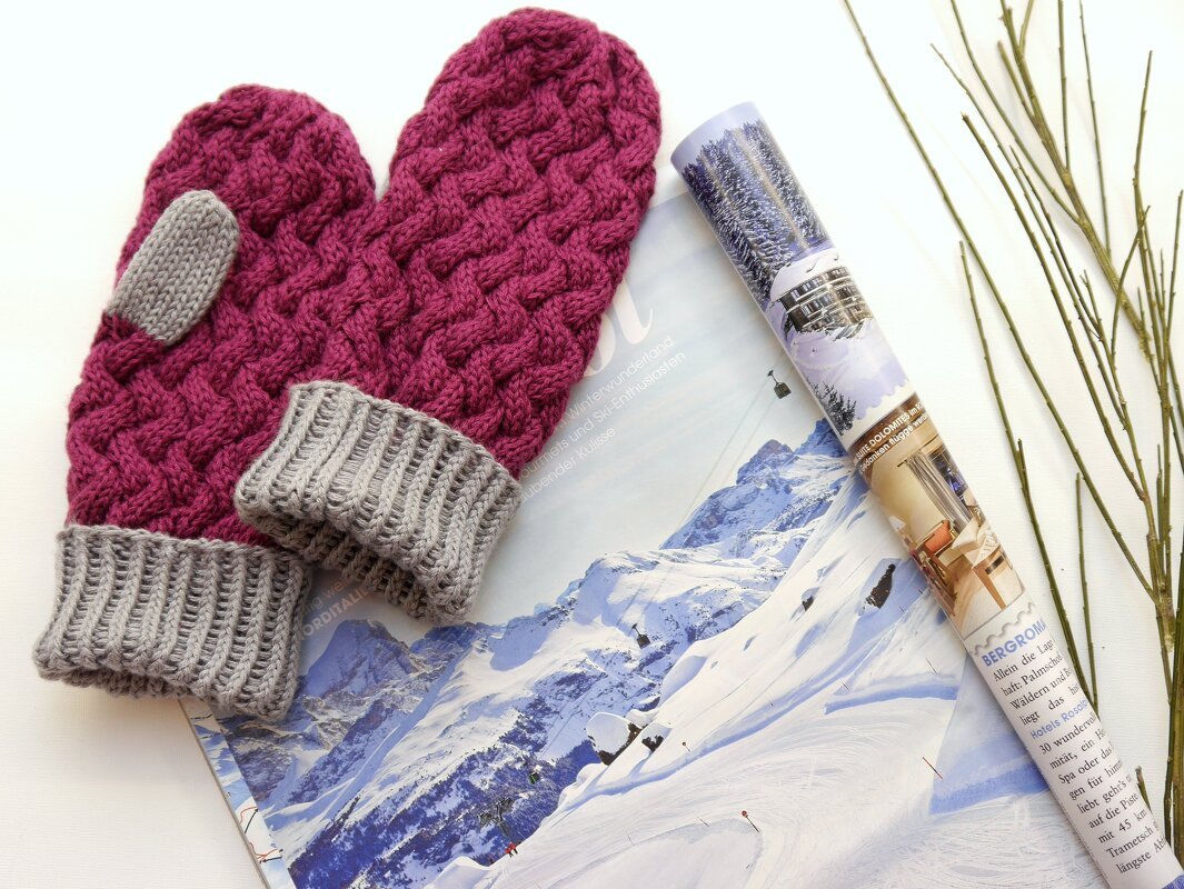 Magenta-Fäustlinge mit Zopfmuster und grauen Rippenbündchen auf einer Winterzeitschrift