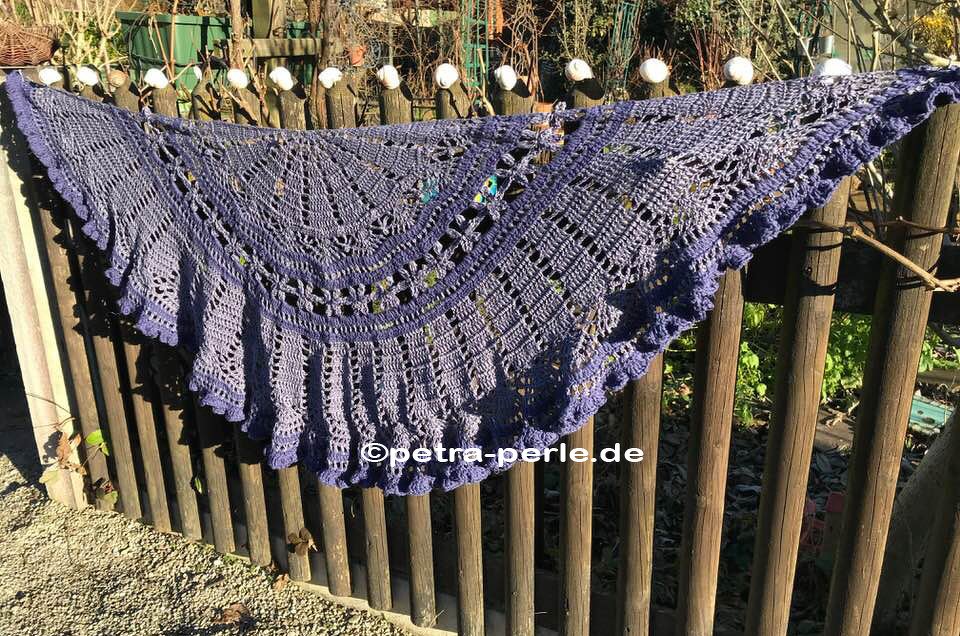 Lila gehäkeltes Dreieckstuch mit feinem Spitzenmuster an einem Holzzaun