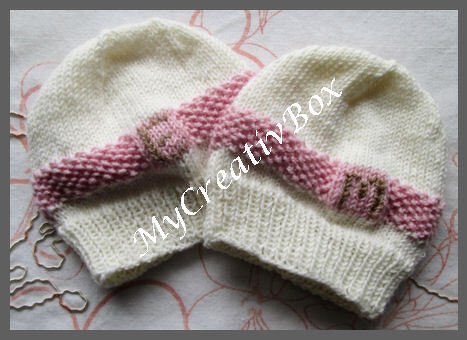 Zwei gestrickte weiße Babymützen mit rosa Zierband