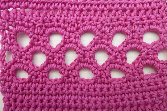 Magentafarbenes Häkelmuster mit regelmäßigen runden Öffnungen