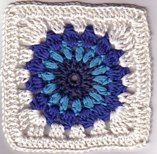 Quadratisches Häkelmotiv mit blauem Sternmuster und weißer Umrandung