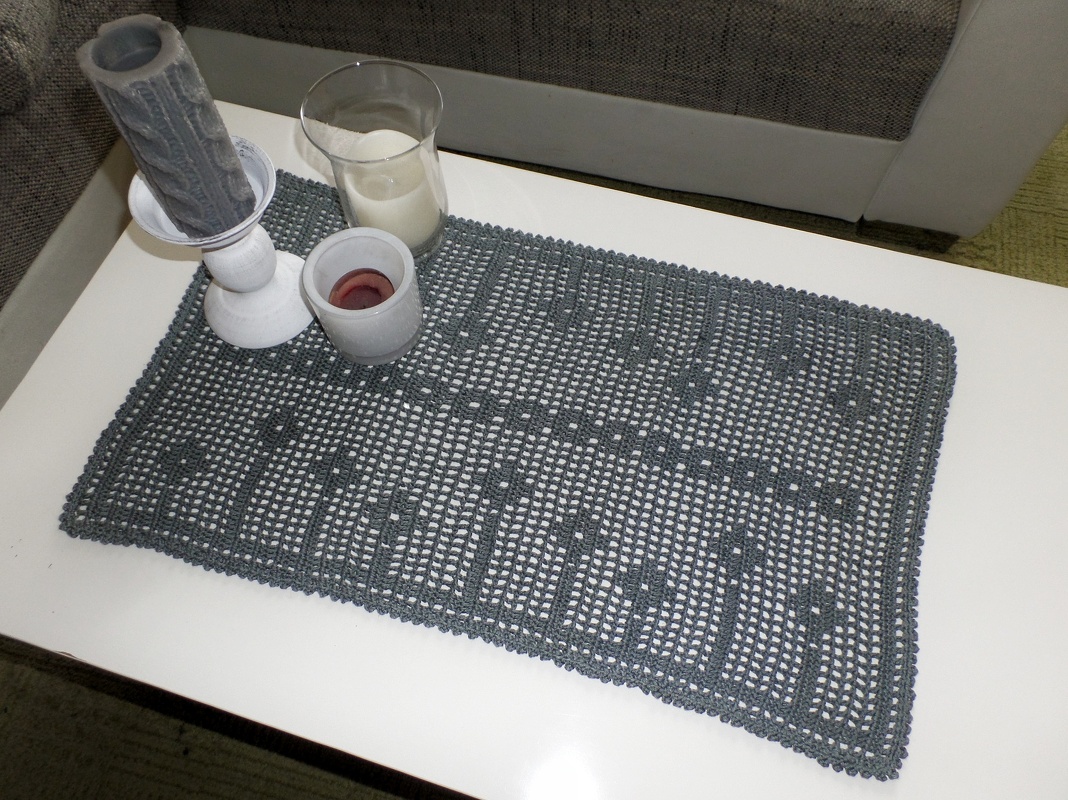 Rechteckiges graues gehäkeltes Deckchen im Filetmuster mit Blumenmotiv auf weißem Tisch, Kerzen als Dekoration