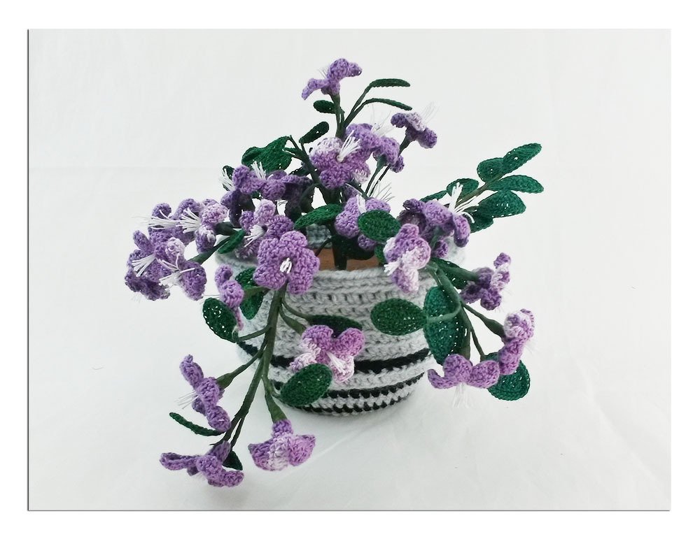 Gehäkelte lila Blumen in grau-schwarz gestreiftem Topf