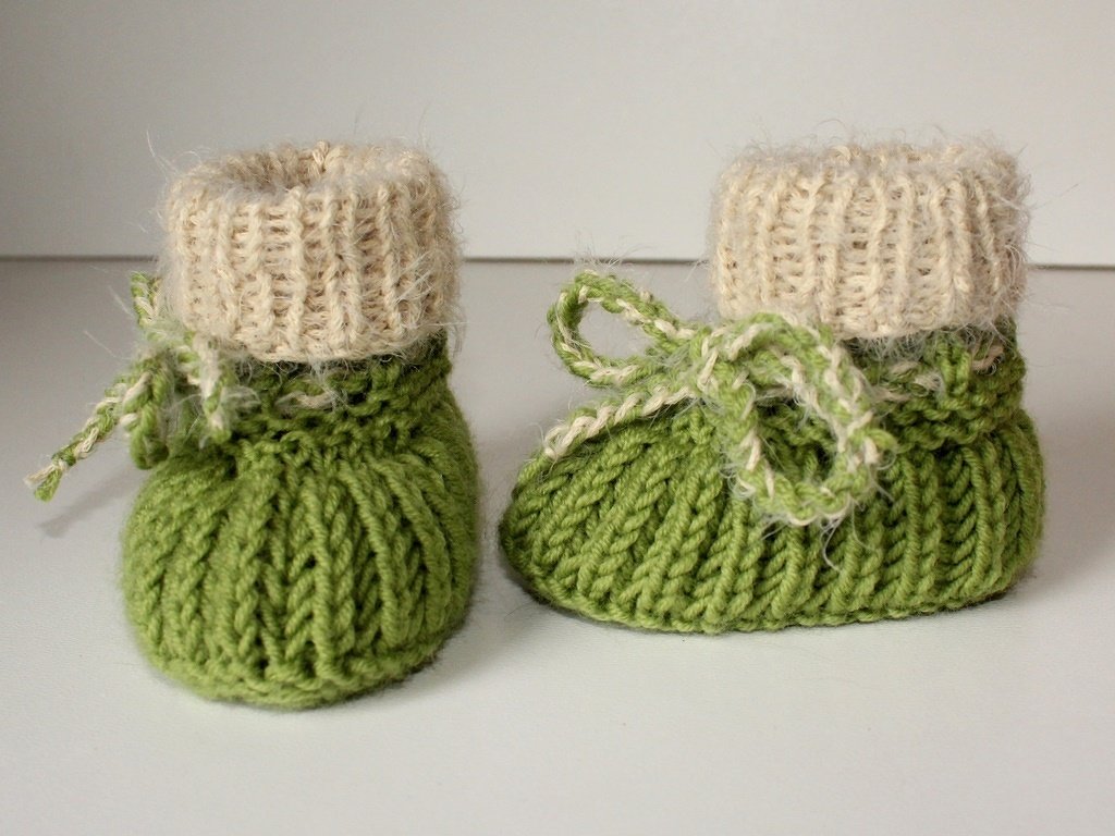 Gestrickte grüne Babyschuhe mit Umschlag und Bindekordel, Nahaufnahme
