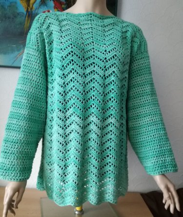 Türkisgrüner, gehäkelter Damenpullover mit Zickzack-Ajourmuster auf einer Schaufensterpuppe.