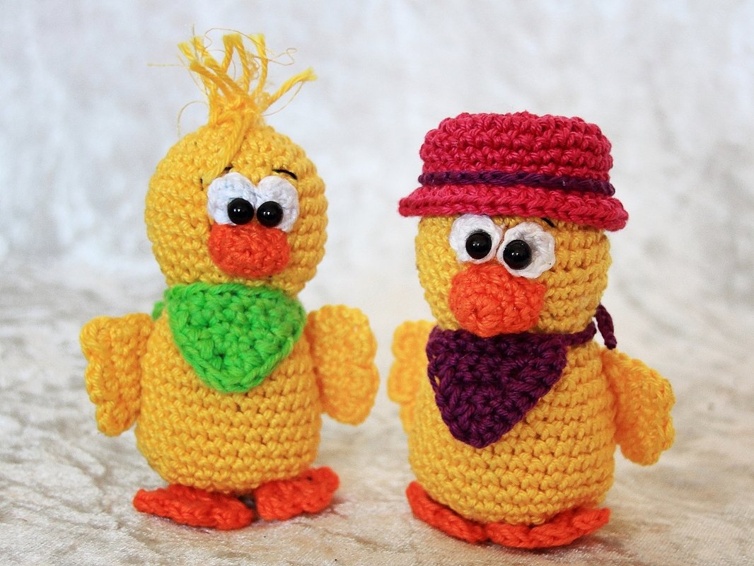 Zwei gelbe Amigurumi-Küken mit Halstüchern und Mütze